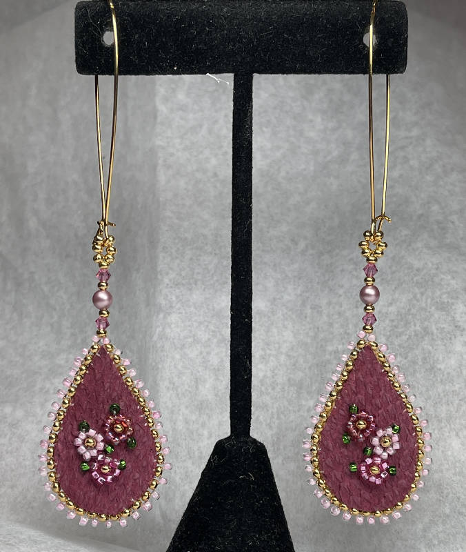 Deep pink dyed fish skin with 3 shades of pink flowers and 24k gold plated centers. Edged w/24k gold plated beads, embellished with light pink Swarovski pearls and fuchsia crystals and hung on gold surgical steel kidney hooks. Backed with moose skin.