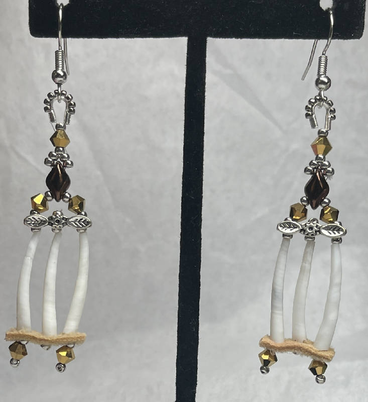 Dentalium earrings w/metal flower spacer and moose skin. Embellished w/2 sizes of silver plated beads, hematite, diamond duo beads and Japanese crystals. On surgical steel hooks.